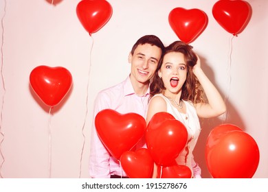 Man With His Lovely Sweetheart Girl Dance And Have Fun At Lover's Valentine Day. Valentine Couple Party. Background Red Balloons Hearts. Love Concept. Crazy. 