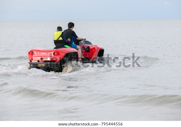 A man\
and his son driving amphibious car into the\
sea