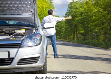 Man Hitchhiking By A Broken Car