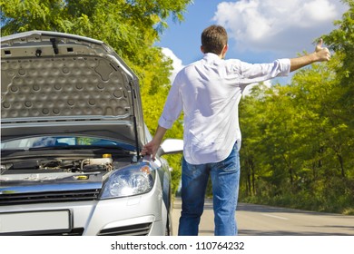 Man Hitchhiking By A Broken Car