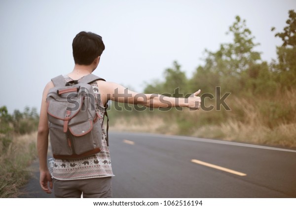 Man hitchhiking on\
road
