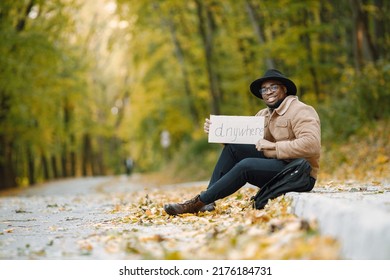  man hitchhiking on a road and holding a sign anywhere