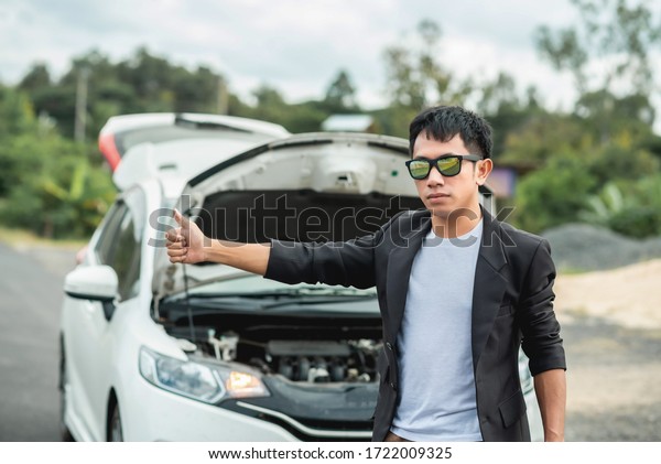 A man was hitchhiking on the side\
of the road. Because his car is broken / waving the\
car