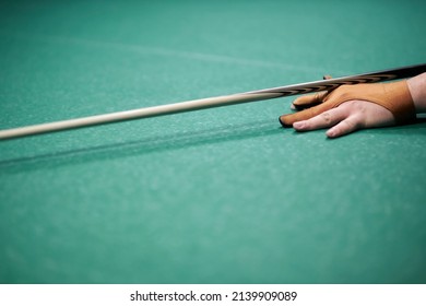 the man hits with a cue. A hand with a cue aiming at a billiard ball at the table. hands holding a cue and trying to drive a billiard hare into the hole. The concept of playing billiards. soft focus