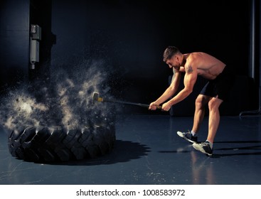 Man Hitting Wheel Tire With Hammer Sledge. Cross-fit Training 