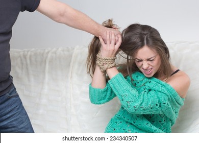 Man Hitting A Young Woman.  Hands Are Tied