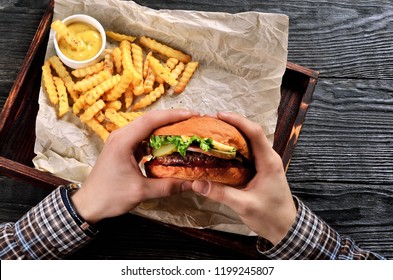 Man hold burger in hands. Meal with burger and french fries.