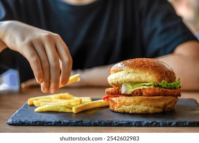 Man hold burger in hands. Meal with burger and french fries. Hamburger. Cheeseburger, hand cut french fries. Hand burger, closeup. Woman holding delicious burger with beef patty, closeup. - Powered by Shutterstock