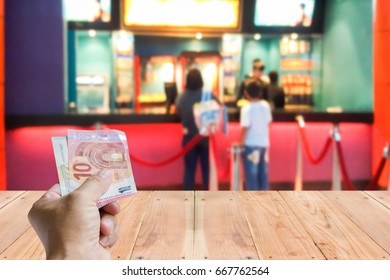 Man Hold Cash, Blur Image Of Movie Ticket Box As Background.