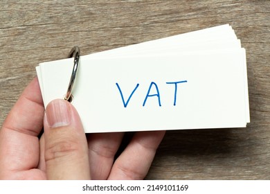 Man hold the flash card with handwriting word VAT (abbreviation of value added tax) on wood background