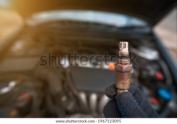 Man hold in hand faulty old oxygen sensor of
exhaust system, car stalled, fault in emission system, maintenance
of motor vehicle. Check and replace faulty lambda sensor. Mechanic
hold oxygen sensor