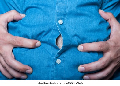 Man Hold Hands Over His Swollen Abdomen In Closeup View As Cramp And Bloating Concept