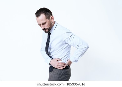 Man hold on to his side and feels severe pain. Adult man in a shirt with pelvic pain suffers and holds on to his hands.