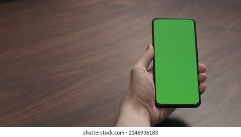 Man Hold Smartphone With Greenscreen On Walnut Table, Wide Photo