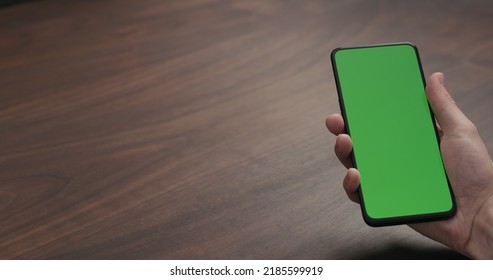 Man Hold Smartphone With Greenscreen On Walnut Table, Wide Photo