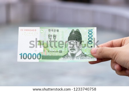Man hold south korea banknote 10000 won on blurred background