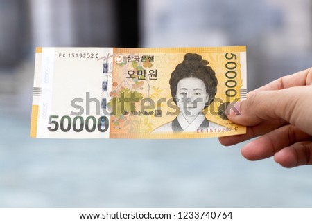 Man hold south korea banknote 50000 won on blurred background