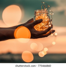 man hold Transparent jar with lights from led on beach in the sunset . Give a Gift. Romantic Hipster Concept. - Powered by Shutterstock