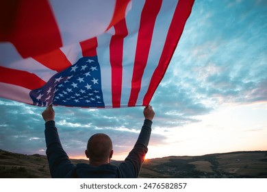 Man holding american USA flag in the sunset. Independence Day or traveling in America concept.