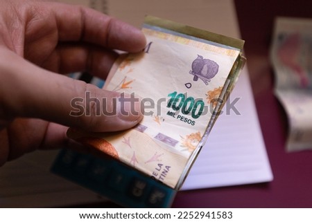 A man holding Argentine peso banknotes. Argentine economy and finance.
