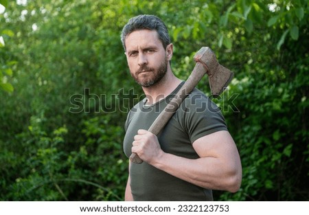 man holding axe outdoor. photo of man with axe. man with axe. man with axe wearing shirt