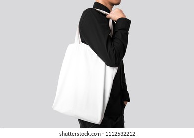 Man is holding bag canvas fabric for mockup blank template isolated on gray background. 
