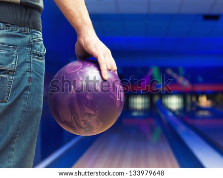 Man holding ball against bowling alley