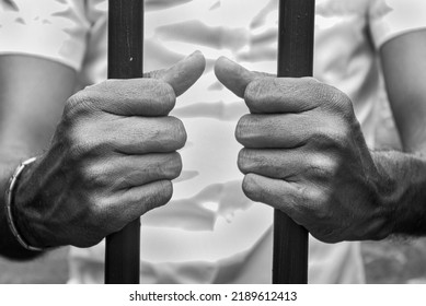 A Man Holding The Bars Of The Prison. Man In Jail. Black And White