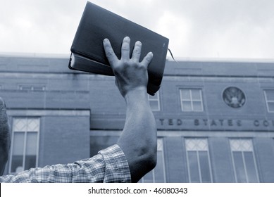 Man Holding Up Bible In Front Of Court House