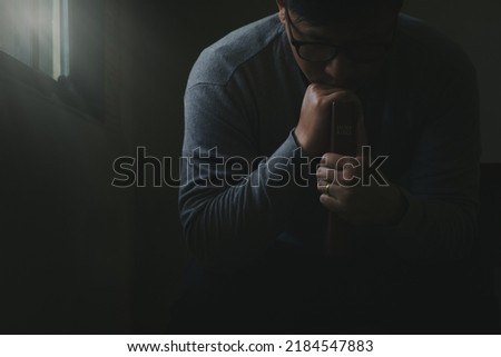 Man holding Bible prays to God with concept of faith, hope, praying for better working life.  trust in god