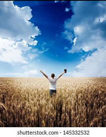 Man Holding Up Bible In A Wheat Field