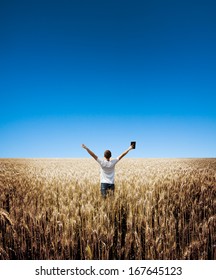 Man Holding Up Bible In A Wheat Field 