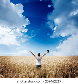 Man Holding Up Bible In A Wheat Field 