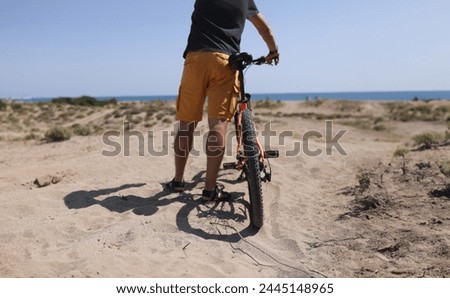 Man holding bike on sand near sea closeup. Achievements of goals concept