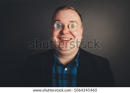 man holding Bitcoin token coins up over his eyes.