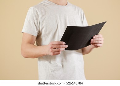 Man Holding Black A4 Paper. Read Booklet. Leaflet Presentation. Pamphlet Hold Hands. Man Show Clear Offset Paper. Sheet Template. Booklet Design Sheet Display Read First Person