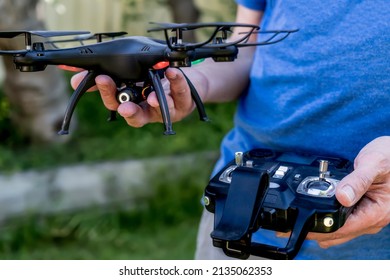 Man Holding Black Drone Camera Quad Copter And Remote Controller. Drone Photography Videography Aerial Wireless Technology. Drone Flight Operator