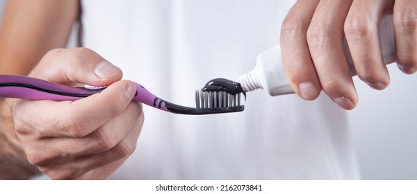 Man Holding Black Toothpaste And Toothbrush.