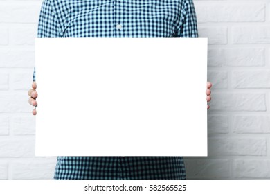 Man Holding Blank Poster On Brick Wall Background