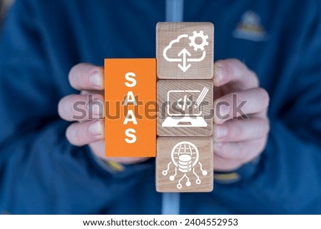 Man holding blocks with icons sees abbreviation: SAAS. Concept of Software As A Service ( SAAS ). Networking Technology Web SEO Marketing concept.