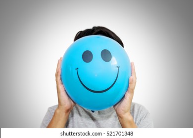 A Man Holding A Blue Balloon With Smile Face Emoticon Instead Of Head. Hiding Some Bad Feeling Just Smiling. Happy Friday