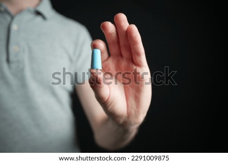 Man holding blue earplug between thumb and index finger