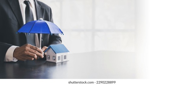 Man holding blue umbrella and white house. An insurance agent is holding a blue umbrella over a modern white house model. Property insurance concept. home and real estate insurance concepts. - Shutterstock ID 2290228899