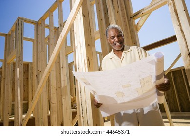 Man Holding Blueprints Near Construction Framing. Horizontally Framed Shot.