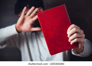 Man Holding A Book Covering His Face