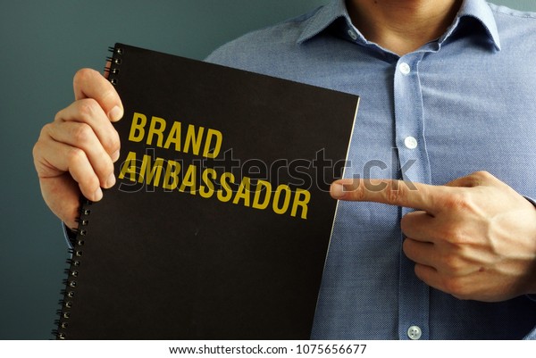 Man is\
holding book with title Brand\
Ambassador.
