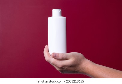 A Man Holding A Bottle Of Lotion In His Hand