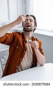 Man Holding Bottle And Pipette While Taking Cbd Oil