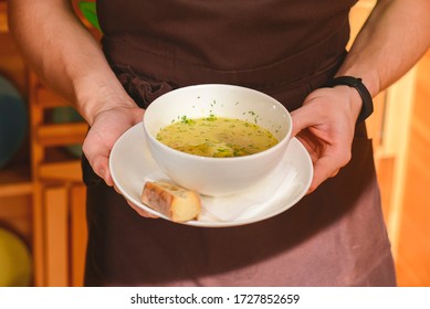 Man Holding A Bowl Of Soup. Waiter Serving Fresh Hot Soup In A Diner Or Restaurant. Healthy Delicious Dinner. Waiter At Work. Restaurant Service.