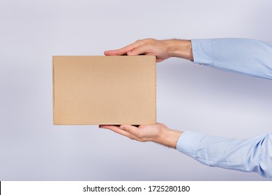 Man Holding Box At Arm's Length. Cardboard Box. Delivery Of Parcels. Side View.